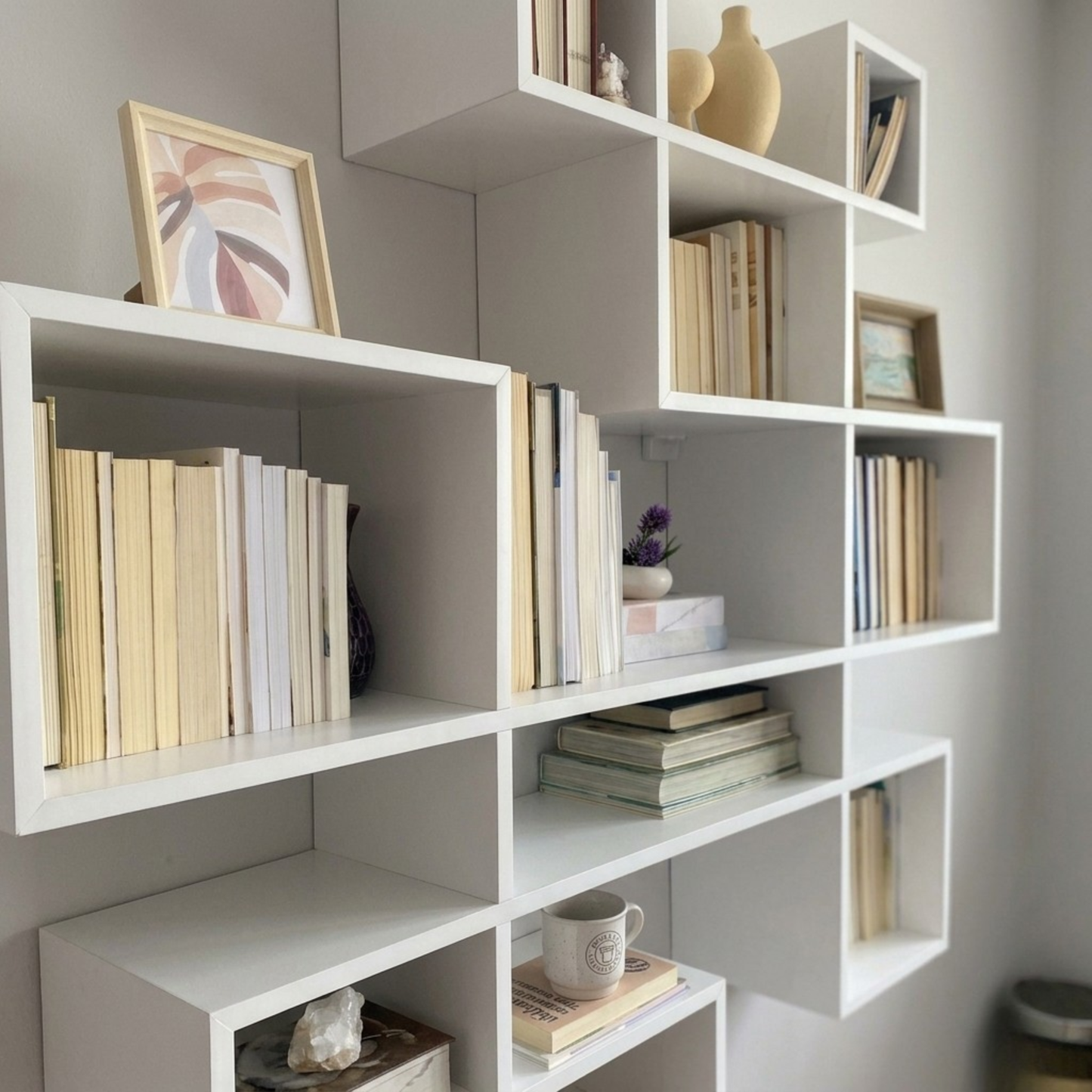 مكتبة حائط معلقة مودرن - أرفف خشبية بيضاء بتصميم هندسي متداخل