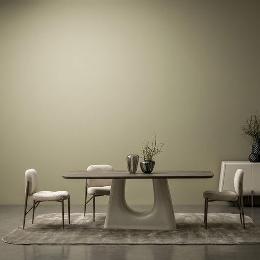 Contemporary oval dining table with a sculptural beige base and textured chairs arranged in a minimalist setting.